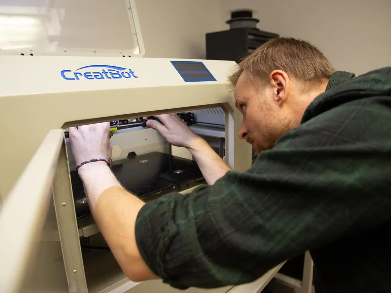 Ein 3Dmensional Mitarbeiter wartet gerade einen 3D Drucker